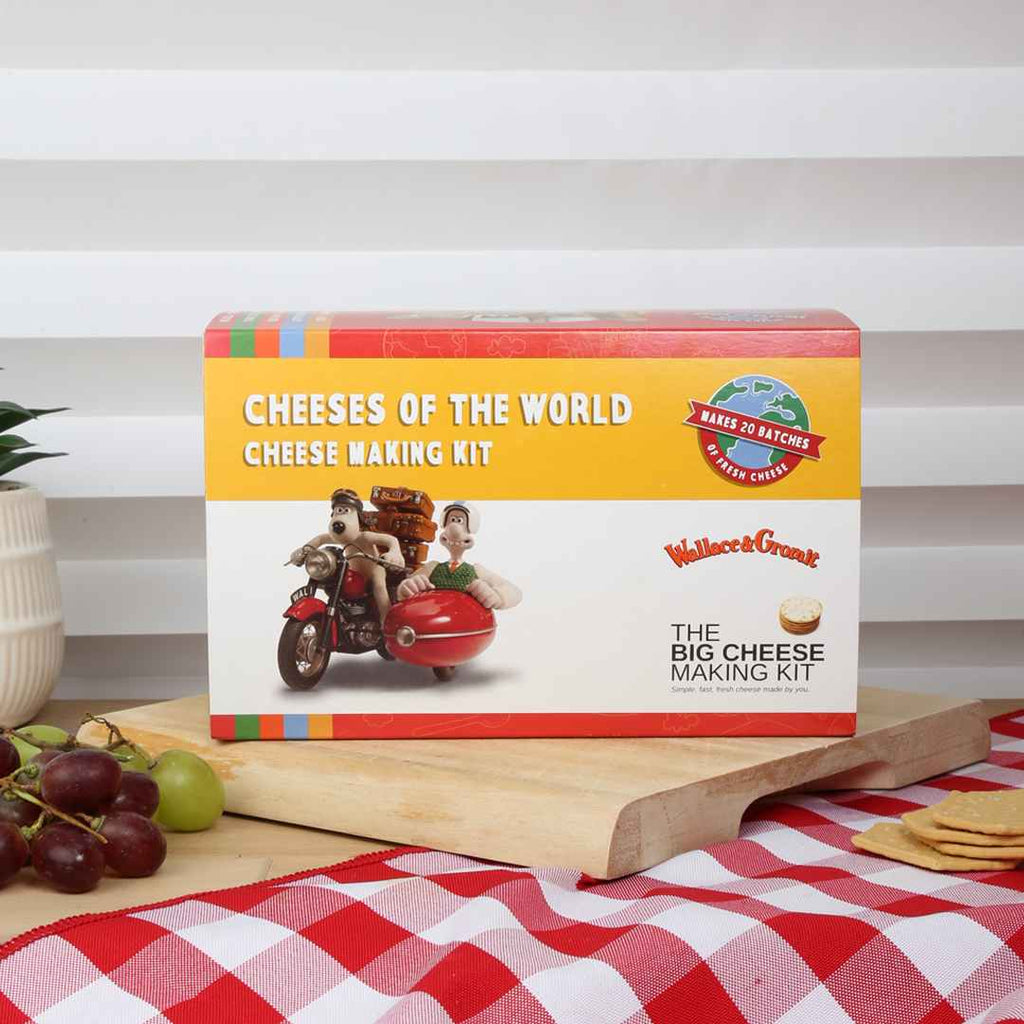 Cheeses of the World cheese making kit on a wooden board with grapes and crackers.