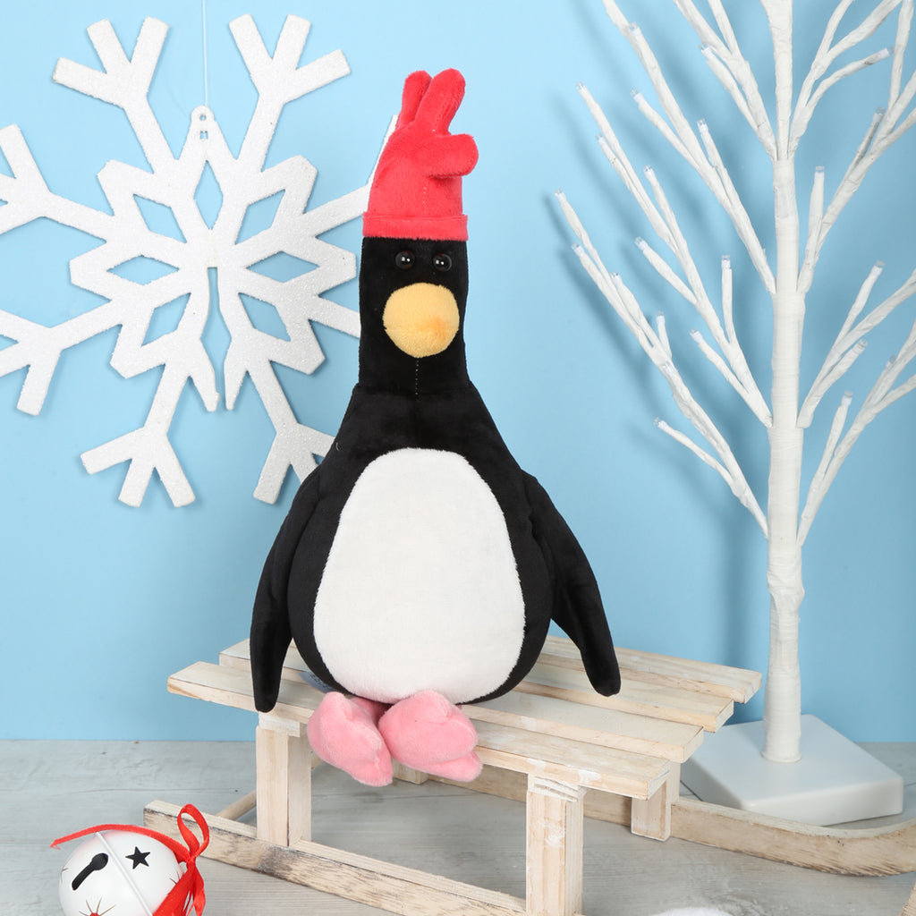 Plush Feathers McGraw with a red hat on a wooden sledge against a light blue wall with white decorative elements.