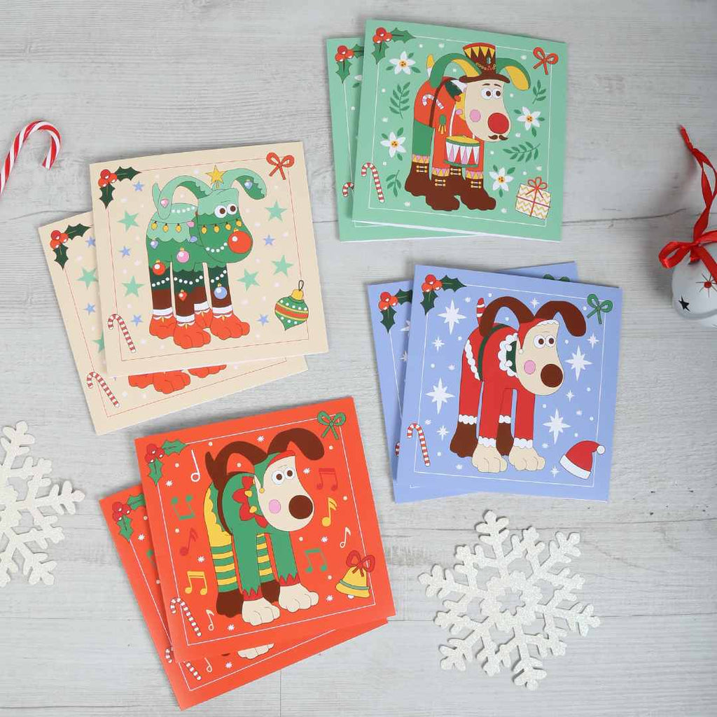 Set of Christmas-themed greeting cards with our favourite festive Gromits on a light wooden surface.