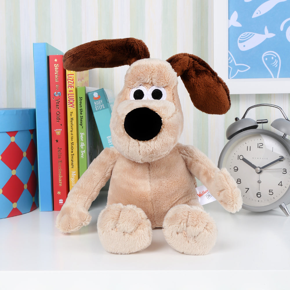 Cute Gromit soft toy on bedroom shelf between books and clock
