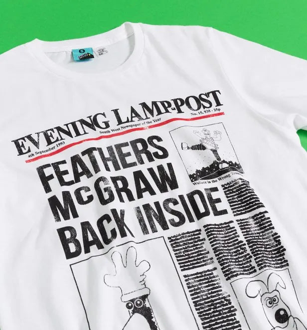 White t-shirt featuring a graphic of a newspaper headline. Headline reads: Feathers McGraw back inside' with pictures of Feathers McGraw, Gromit and The Wrong Trousers. 