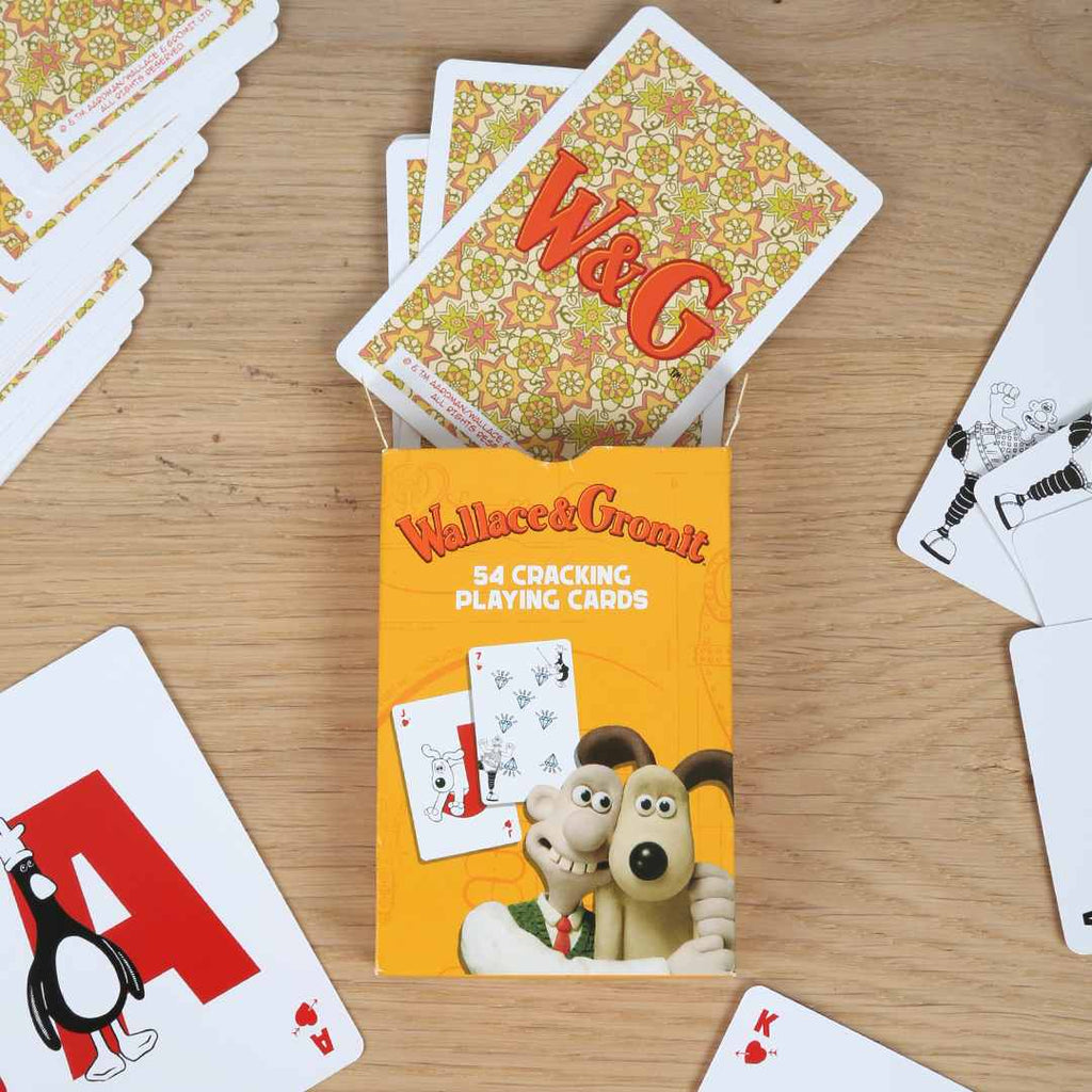 Pack of Wallace & Gromit playing cards on a wooden surface with some cards spread out.