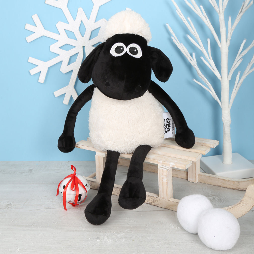 Plush toy Shaun the Sheep with a white hat on a wooden sledge against a light blue background with decorative elements.