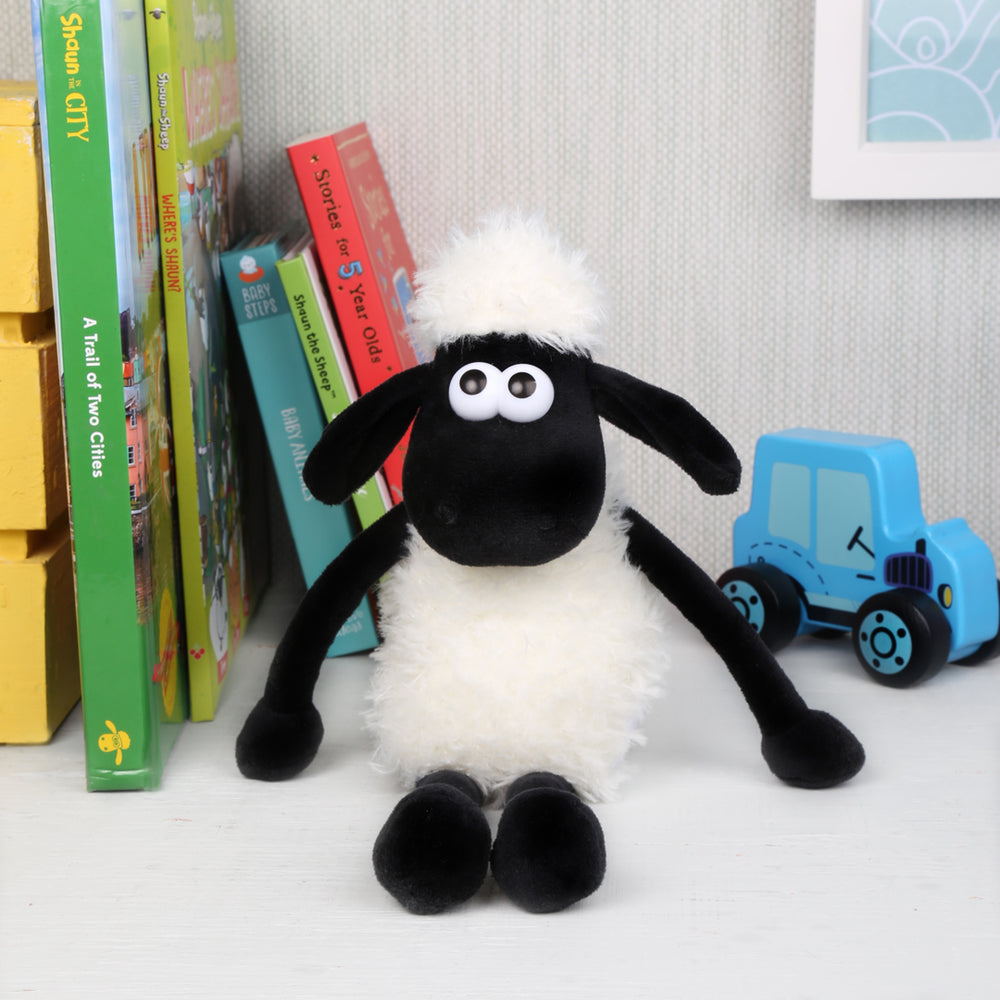 Small Shaun the sheep soft toy, fluffy and cute, sat on shelf amongst colourful toys