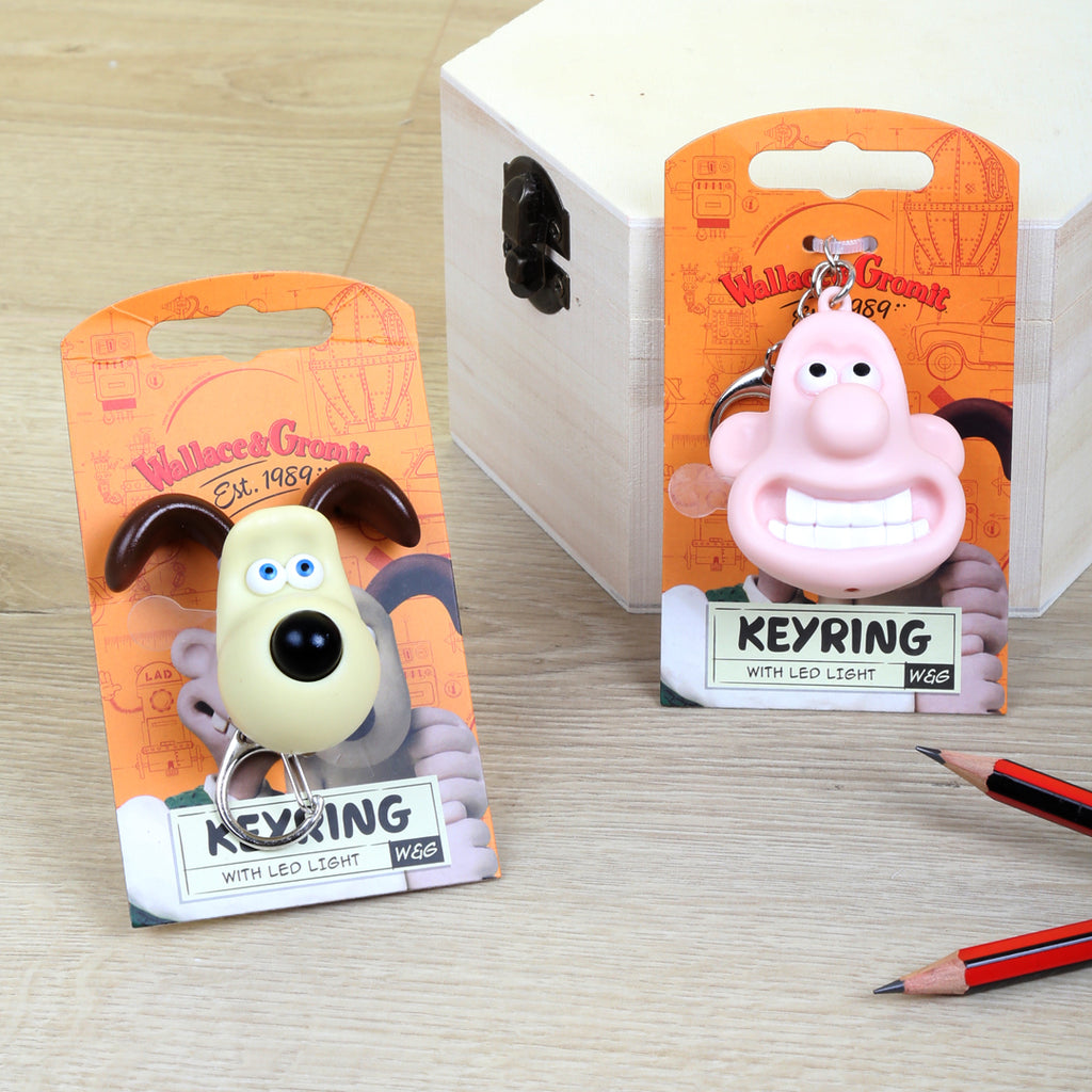 Two keyrings with packaging featuring cartoon characters on a wooden surface.