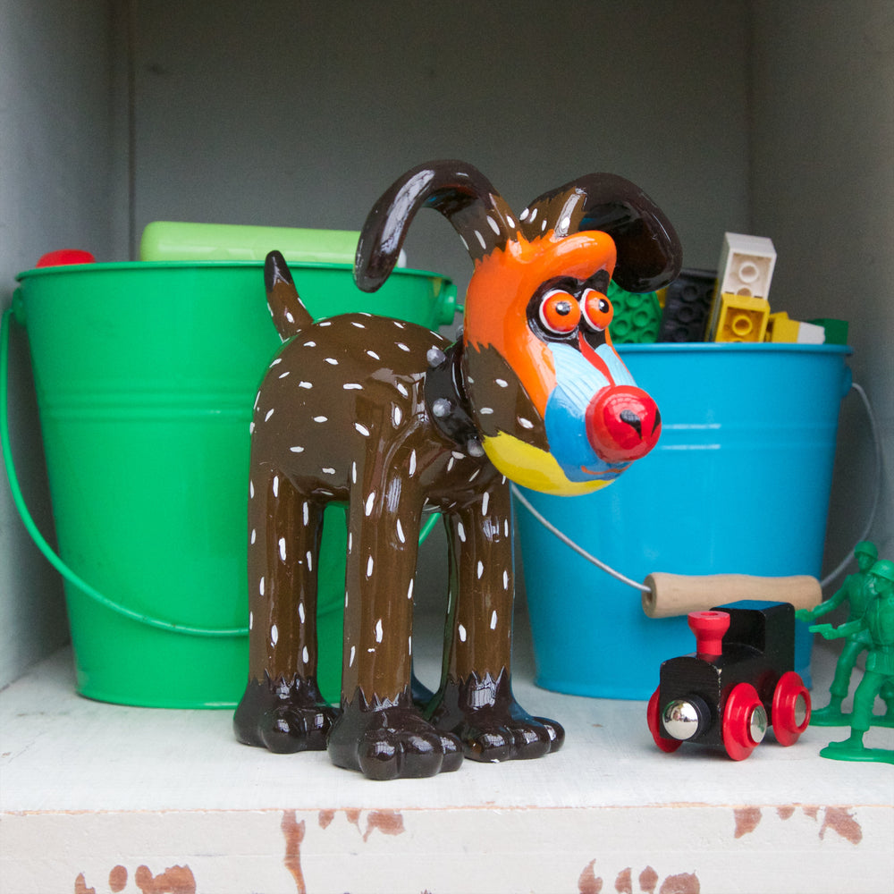 A Mandrill's Best Friend Gromit Figurine stood in front of blue and green buckets full of lego pieces. 