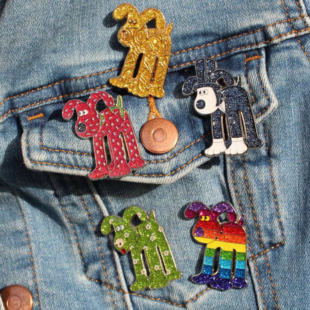 Collection of Gromit Unleashed sparkly pin badges photographed on denim jacket