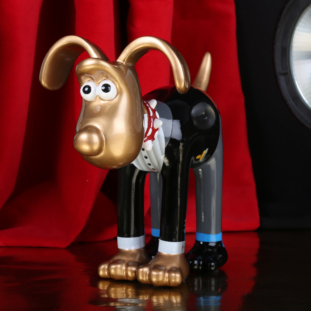 Golden Gromit figurine in tuxedo with award in his pocket, pictured amongst red carpet scene